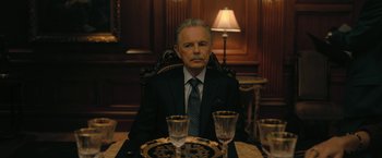 Movie still from “The Fall of the House of Usher” (2023), directed by Mike Flanagan – An older man sitting at a dinner table with two empty glasses; Close Up shot, Over the shoulder angle