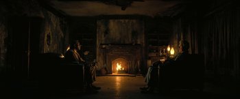 Movie still from “The Fall of the House of Usher” (2023), directed by Mike Flanagan – Two people sitting in front of a fire in a living room; Wide shot, Low angle