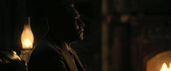Movie still from “The Fall of the House of Usher” (2023), directed by Mike Flanagan – A man wearing a suit and tie in the dark; Close Up shot, Over the shoulder angle
