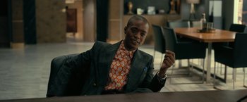 Movie still from “The Fall of the House of Usher” (2023), directed by Mike Flanagan – A man sitting at a table in a suit and tie; Medium shot, Over the shoulder angle