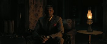 Movie still from “The Fall of the House of Usher” (2023), directed by Mike Flanagan – A man sitting on a couch in a room; Medium shot, Low angle
