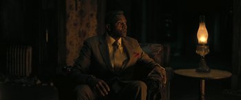 Movie still from “The Fall of the House of Usher” (2023), directed by Mike Flanagan – A man in a suit and tie sitting in a chair; Medium shot, Low angle