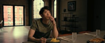 Movie still from “The Fall of the House of Usher” (2023), directed by Mike Flanagan – A man sitting at a table eating food from a plate; Medium shot, Over the shoulder angle