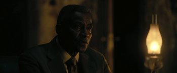 Movie still from “The Fall of the House of Usher” (2023), directed by Mike Flanagan – A man wearing a suit and tie in the dark; Close Up shot, Over the shoulder angle