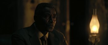 Movie still from “The Fall of the House of Usher” (2023), directed by Mike Flanagan – A man wearing a suit and tie in the dark; Close Up shot, Over the shoulder angle