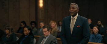 Movie still from “The Fall of the House of Usher” (2023), directed by Mike Flanagan – A man standing in front of other people in a courtroom; Medium shot, Over the shoulder angle