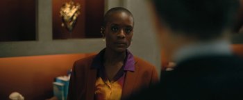 Movie still from “The Fall of the House of Usher” (2023), directed by Mike Flanagan – A woman in a brown jacket and a purple shirt; Close Up shot, Over the shoulder angle