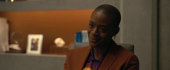 Movie still from “The Fall of the House of Usher” (2023), directed by Mike Flanagan – A woman in a brown jacket smiling for the camera; Close Up shot, Over the shoulder angle