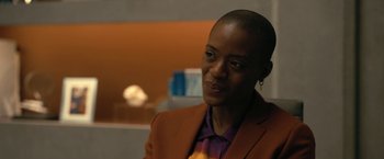 Movie still from “The Fall of the House of Usher” (2023), directed by Mike Flanagan – A woman wearing a brown jacket and purple shirt; Close Up shot, Over the shoulder angle