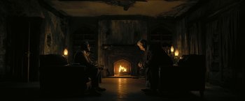 Movie still from “The Fall of the House of Usher” (2023), directed by Mike Flanagan – Two men sitting in front of a fire in a living room; Wide shot, High angle