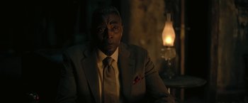 Movie still from “The Fall of the House of Usher” (2023), directed by Mike Flanagan – A man wearing a suit and tie sitting in a chair; Close Up shot, Over the shoulder angle