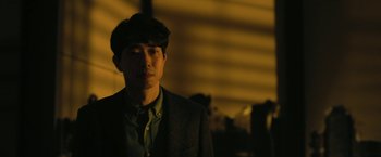 Movie still from “The Fall of the House of Usher” (2023), directed by Mike Flanagan – A man in a suit and hat is looking at the camera; Close Up shot, Over the shoulder angle