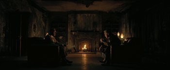 Movie still from “The Fall of the House of Usher” (2023), directed by Mike Flanagan – A group of people sitting in front of a fire place; Wide shot, Over the shoulder angle