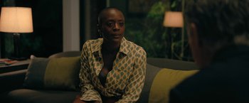 Movie still from “The Fall of the House of Usher” (2023), directed by Mike Flanagan – A woman sitting on a couch in front of a green wall; Medium shot, Over the shoulder angle