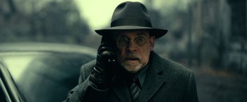 Movie still from “The Fall of the House of Usher” (2023), directed by Mike Flanagan – An older man in a hat and glasses holding a cell phone to his ear; Close Up shot, Low angle