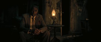 Movie still from “The Fall of the House of Usher” (2023), directed by Mike Flanagan – A man sitting in a chair in front of an oil lamp; Medium shot, Low angle