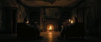 Movie still from “The Fall of the House of Usher” (2023), directed by Mike Flanagan – Two people sitting in front of a fire in a living room; Wide shot, High angle