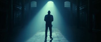 Movie still from “The Fall of the House of Usher” (2023), directed by Mike Flanagan – A man standing in a dark room with a light shining on him; Wide shot, Low angle