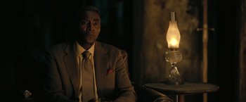 Movie still from “The Fall of the House of Usher” (2023), directed by Mike Flanagan – A man in a suit sitting in front of a lamp; Close Up shot, Low angle