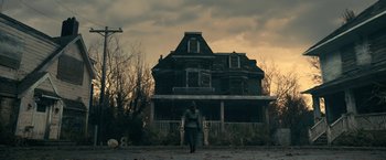 Movie still from “The Fall of the House of Usher” (2023), directed by Mike Flanagan – A person standing in front of a large house; Extreme Wide shot, Low angle