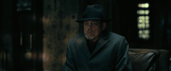 Movie still from “The Fall of the House of Usher” (2023), directed by Mike Flanagan – An older man wearing a suit and a hat; Close Up shot, Over the shoulder angle