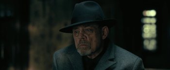 Movie still from “The Fall of the House of Usher” (2023), directed by Mike Flanagan – An older man wearing a hat and glasses; Close Up shot, Over the shoulder angle