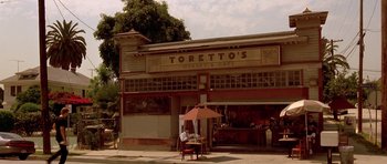Movie still from “The Fast and the Furious” (2001), directed by Rob Cohen – An outdoor cafe with a person sitting at a table; Wide shot, High angle