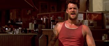 Movie still from “The Fast and the Furious” (2001), directed by Rob Cohen – A man in a red tank top is standing in front of a counter; Close Up shot, Low angle