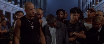 Movie still from “The Fast and the Furious” (2001), directed by Rob Cohen – A group of men standing next to each other in front of a building; Medium shot, Low angle