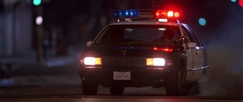 Movie still from “The Fast and the Furious” (2001), directed by Rob Cohen – A police car with its lights turned on at night; Wide shot, Low angle