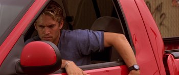 Movie still from “The Fast and the Furious” (2001), directed by Rob Cohen – A man sitting in the driver's seat of a red car; Close Up shot, Over the shoulder angle