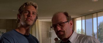 Movie still from “The Fast and the Furious” (2001), directed by Rob Cohen – A man with a beard and glasses is looking at a man with a beard and eyeglasses; Close Up shot, Low angle