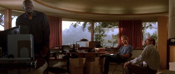 Movie still from “The Fast and the Furious” (2001), directed by Rob Cohen – A man sitting in front of a large window in a living room; Wide shot, Low angle