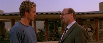 Movie still from “The Fast and the Furious” (2001), directed by Rob Cohen – Two men standing next to each other in front of a building; Close Up shot, Over the shoulder angle