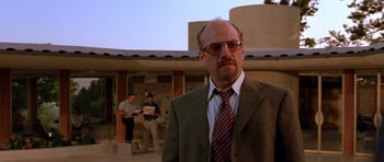 Movie still from “The Fast and the Furious” (2001), directed by Rob Cohen – A man in a suit and tie standing in front of a building; Medium shot, Low angle