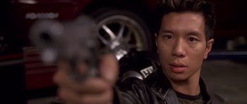 Movie still from “The Fast and the Furious” (2001), directed by Rob Cohen – A man holding a gun in front of a car; Close Up shot, High angle