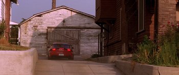 Movie still from “The Fast and the Furious” (2001), directed by Rob Cohen – A red car parked in front of an old building; Wide shot, Low angle