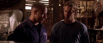 Movie still from “The Fast and the Furious” (2001), directed by Rob Cohen – Two men standing next to each other in a warehouse; Close Up shot, Over the shoulder angle