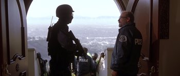 Movie still from “The Fast and the Furious” (2001), directed by Rob Cohen – A man in a police uniform talking to another man in a blue jacket; Medium shot, Low angle