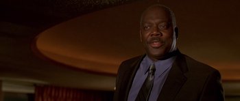 Movie still from “The Fast and the Furious” (2001), directed by Rob Cohen – A man wearing a suit and tie standing in front of a wall; Close Up shot, Low angle