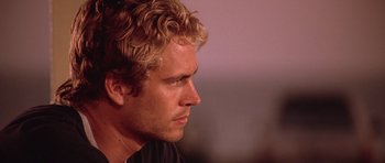 Movie still from “The Fast and the Furious” (2001), directed by Rob Cohen – A person with curly blonde hair; Close Up shot, Over the shoulder angle