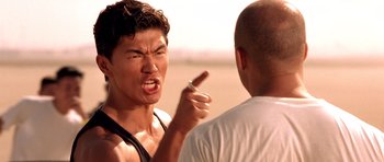 Movie still from “The Fast and the Furious” (2001), directed by Rob Cohen – A man in a white shirt is pointing at another man in a white shirt; Close Up shot, Over the shoulder angle