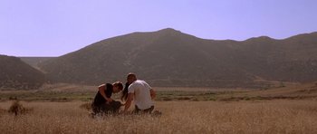 Movie still from “The Fast and the Furious” (2001), directed by Rob Cohen – A man kneeling down next to a woman in a field; Wide shot, Low angle
