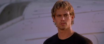 Movie still from “The Fast and the Furious” (2001), directed by Rob Cohen – A man that is standing in front of a wall; Close Up shot, Over the shoulder angle