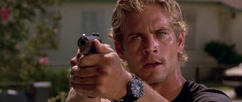 Movie still from “The Fast and the Furious” (2001), directed by Rob Cohen – A man holding a gun in his hand; Close Up shot, Over the shoulder angle