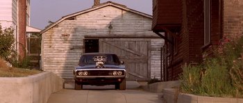 Movie still from “The Fast and the Furious” (2001), directed by Rob Cohen – An old car parked in front of an old building; Wide shot, Low angle