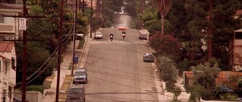 Movie still from “The Fast and the Furious” (2001), directed by Rob Cohen – Two motorcycles are riding down the street in the middle of the day; Extreme Wide shot, High angle