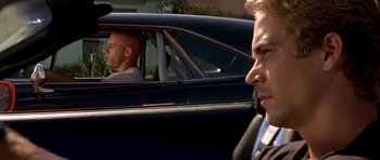 Movie still from “The Fast and the Furious” (2001), directed by Rob Cohen – A man in a suit sitting in the driver's seat of a car; Close Up shot, Over the shoulder angle