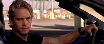 Movie still from “The Fast and the Furious” (2001), directed by Rob Cohen – A young man driving a car on the street; Close Up shot, Over the shoulder angle