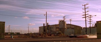 Movie still from “The Fast and the Furious” (2001), directed by Rob Cohen – An industrial building with power lines in the background; Extreme Wide shot, High angle